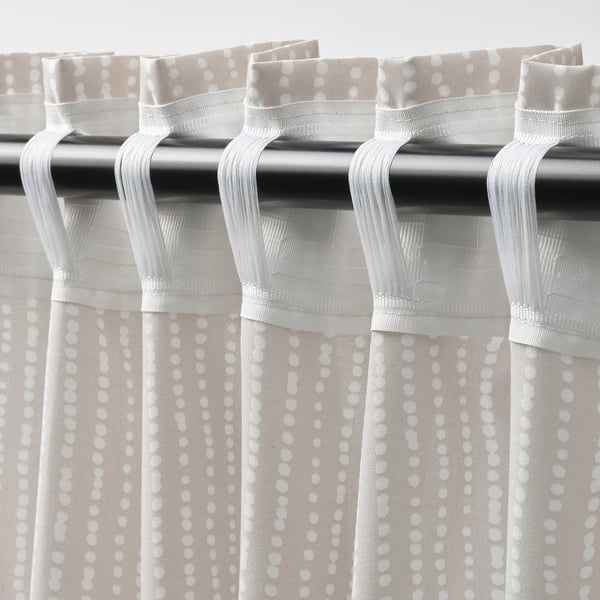 Curtains with beige and white dot patterns hang from hooks, creating pleats. They allow daylight while providing privacy.
