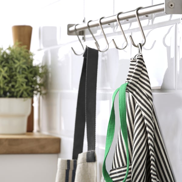 Metal hooks hold striped apron and utensils in a kitchen.