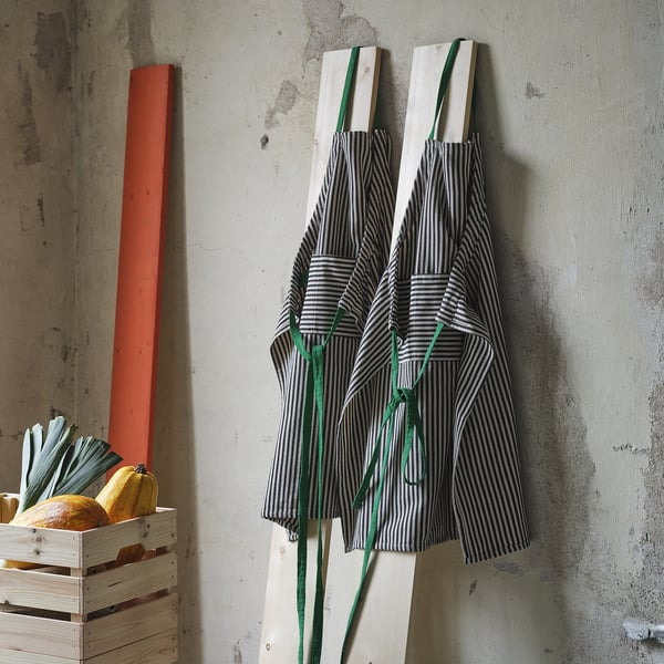 Two striped mã¤vinn aprons hang near veggie crate.