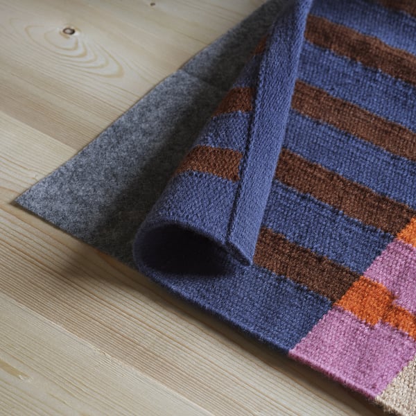 Striped jute and wool rug on wooden floor. Colourful stripes and natural texture, ideal for hallways or bedsides.