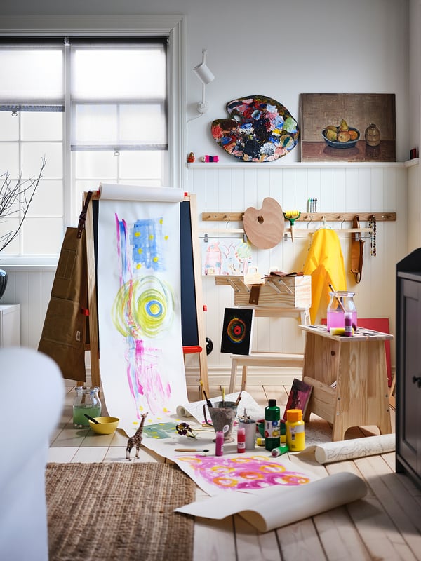 Art studio with easels, paints, papers, and framed paintings.