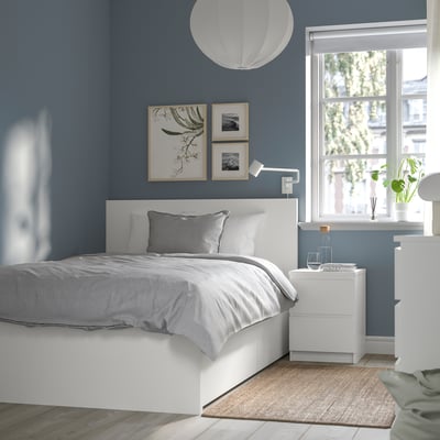 Minimalist bedroom with blue walls, MALM bed, grey linens, wooden bedside table, art, large window.