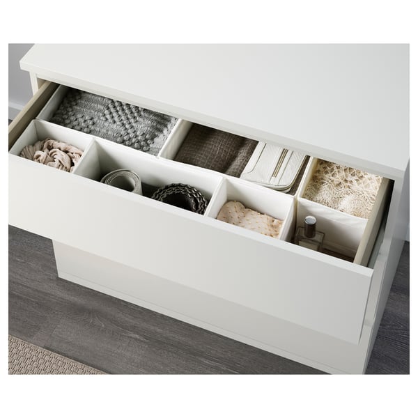 Open white chest drawer. Organised with various folded clothes and small items in compartments.