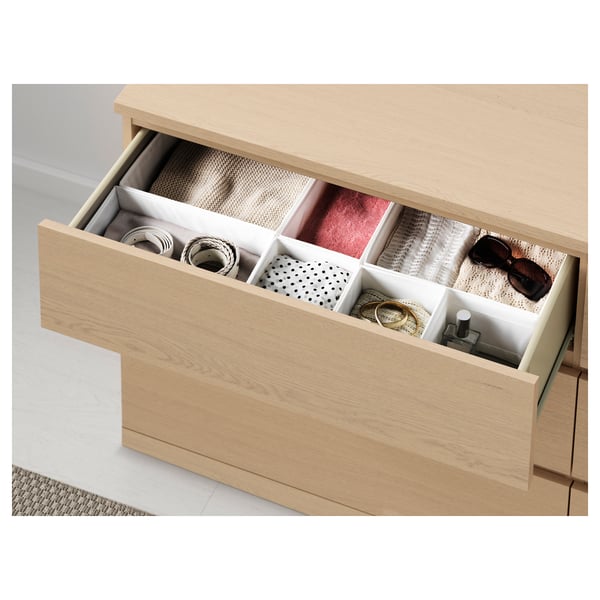 Light wood dresser with open drawer showing neatly organised accessories in compartments.