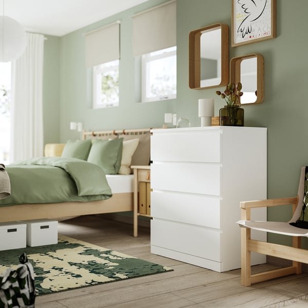 Modern bedroom with white MALM chest of drawers between windows and bed, offering ample storage in a sleek, minimalist design.