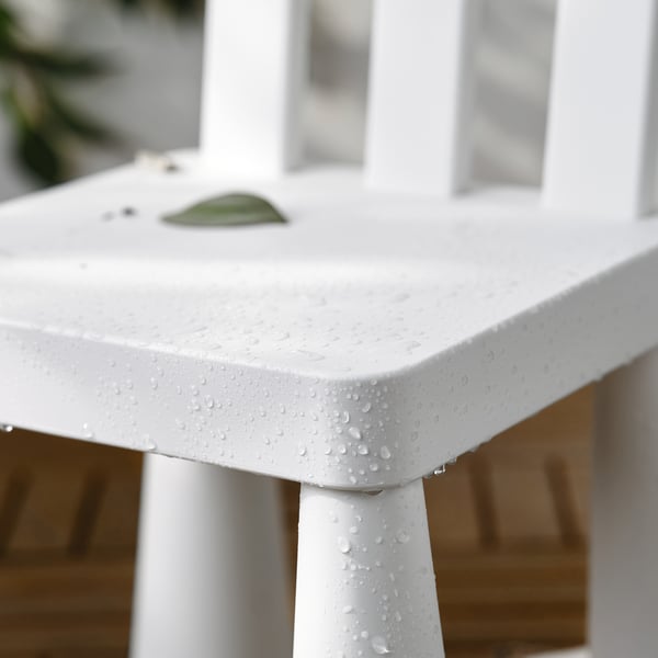 White kids table with water droplets, small green leaf on top.