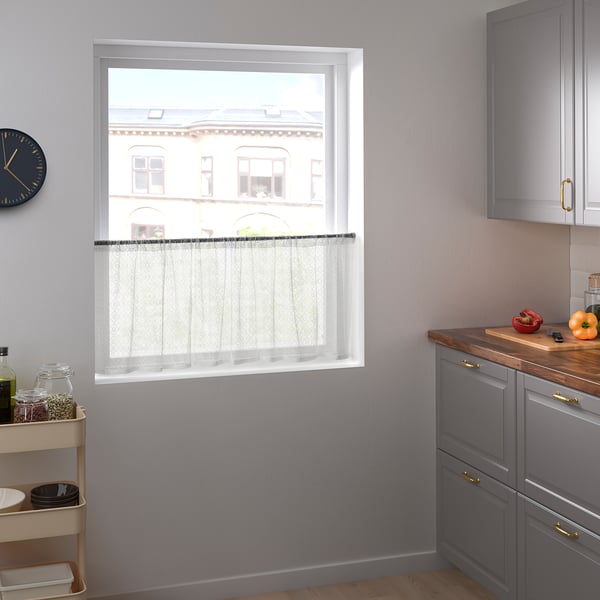 Modern kitchen with sheer white MARIELENA curtains, gray cabinets, kitchen trolley, and clock.