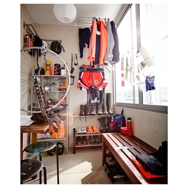 Cosy room with jackets, tools, stool, bench, & bike wheel.