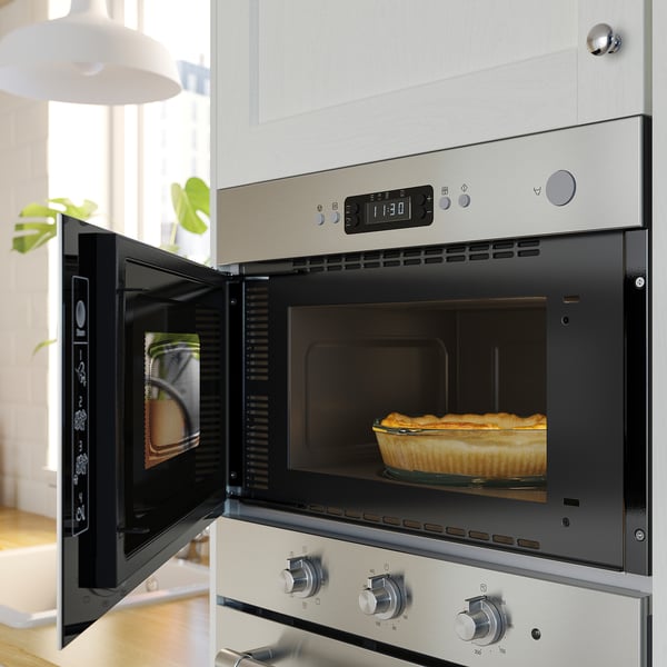 Open stainless steel oven with baked dish inside, digital display on top, modern kitchen setting.
