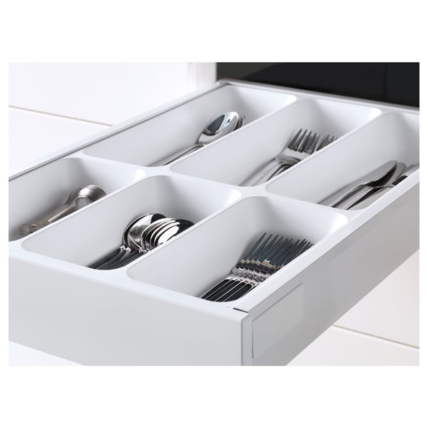 White kitchen drawer organiser holding cutlery: spoons, forks, knives in compartments.