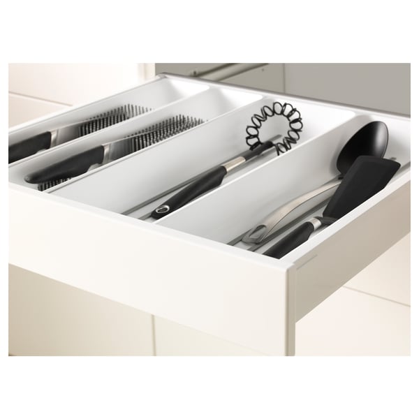 Open kitchen drawer showing organised utensils, knives, and whisks in sections. White drawer has self-closing feature.