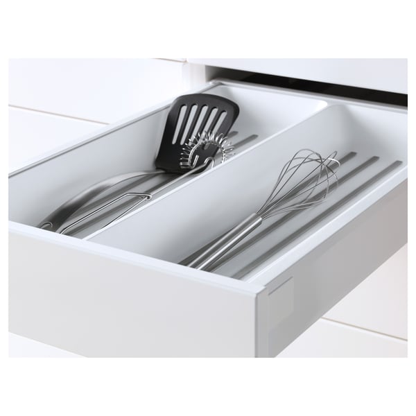 White kitchen drawer, part of IKEAs METOD system, holds utensils including a spatula and whisk, featuring smooth closing and self-closing mechanisms.