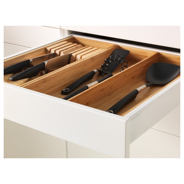Wooden knife drawer organiser in white cabinet with black-handled knives and utensils.