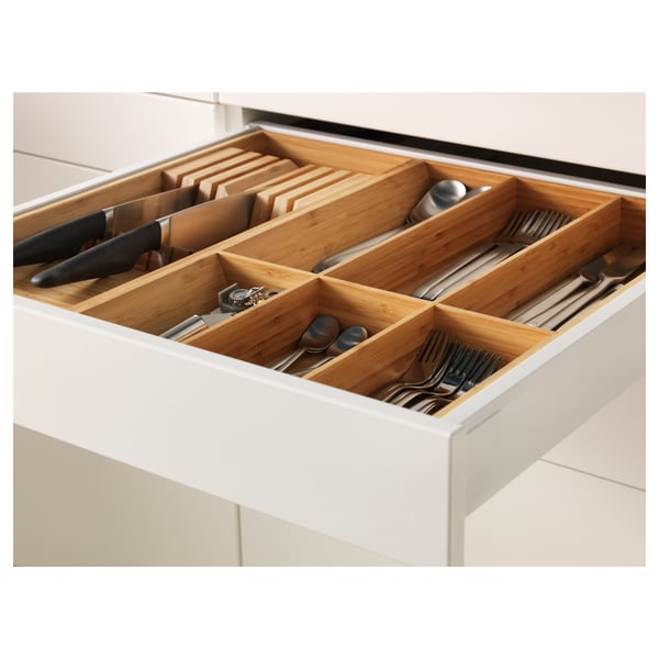 Organised kitchen drawer with bamboo dividers storing knives, forks, spoons, and cooking utensils. Drawers are self-closing with smooth runners.