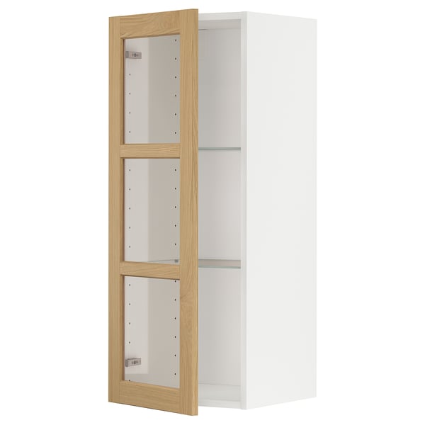 A white METOD kitchen cabinet with adjustable shelves and a light wooden frame. It glass doors with oak veneer.
