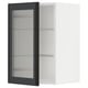 A white METOD kitchen cabinet with a black glass door featuring a reeded design. The cabinet has two glass shelves.