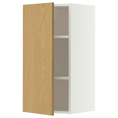 A white METOD wall cabinet with a light oak door open, revealing two glass shelves inside.