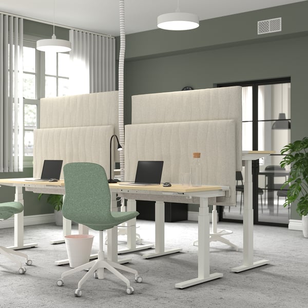 Office space with MITTZON acoustic screens in beige. Green chairs at white desks with laptops. Large windows with curtains.