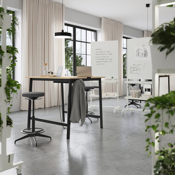 Modern office with high tables and stools, ideal for standing or sitting meetings; includes footrests and cable management for convenience.
