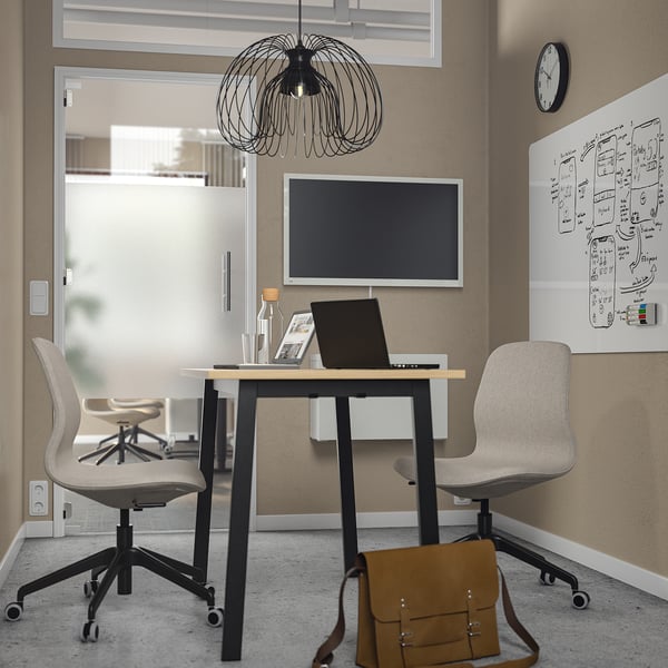 Modern office space with MITTZON table and chairs, laptop, clock, and notes on wall.