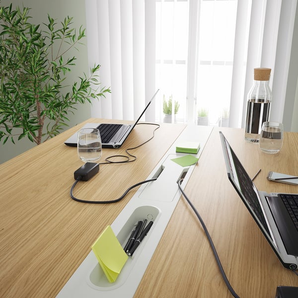 Modern conference table with cable management, pen holders, and footrest. Ergonomic for sitting or standing.