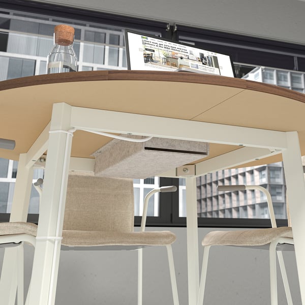 Modern round conference table with beech veneer top and white frame, shown with light-colored seats, designed for small group discussions.