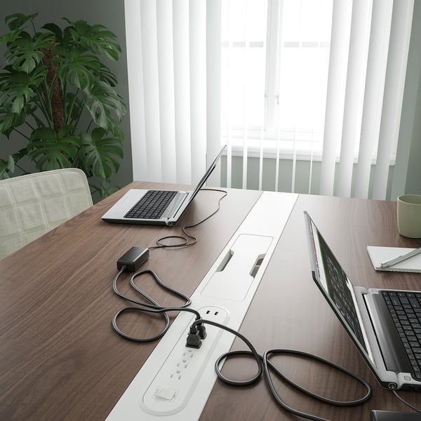 Conference table with laptops, power strips, and plant. Perfect for meetings and work with built-in cable management.