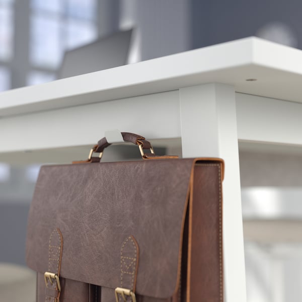 Leather bag hangs on hook under white high table, showing sturdy design and practical storage.