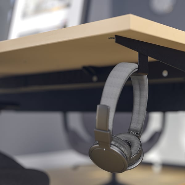 Modern office desk with height-adjustable legs and built-in hooks for headphones or bags.