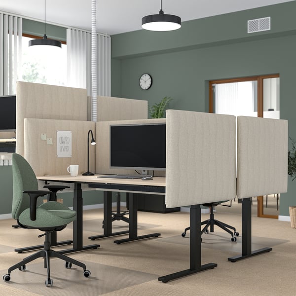 Modern office with MITTZON sit/stand desks, green chairs, acoustic screens, and dual monitors, against green walls.