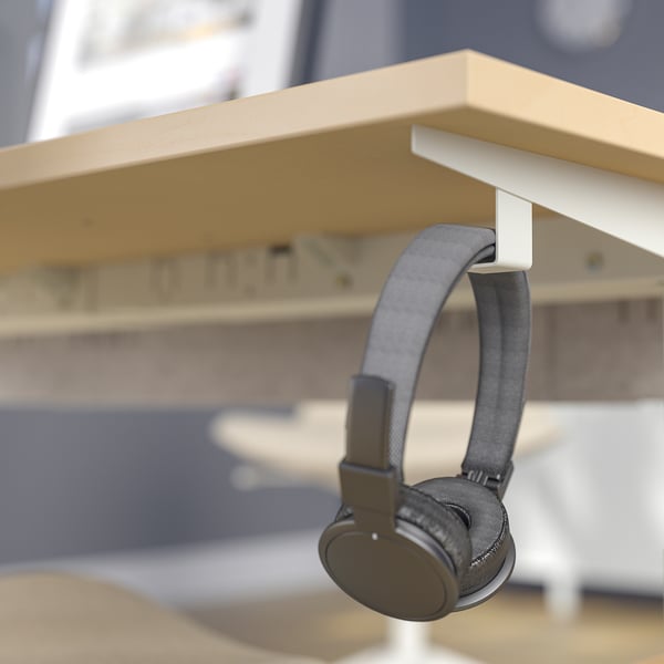 Headphones hang on hook under adjustable desk.