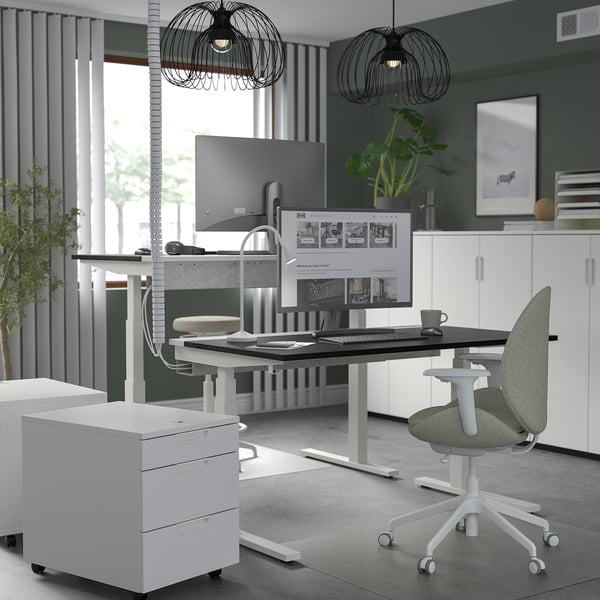 The MITTZON sit-stand desk two monitors, a green chair & pendant lights. Its white, modern, & spacious with adjustable height.