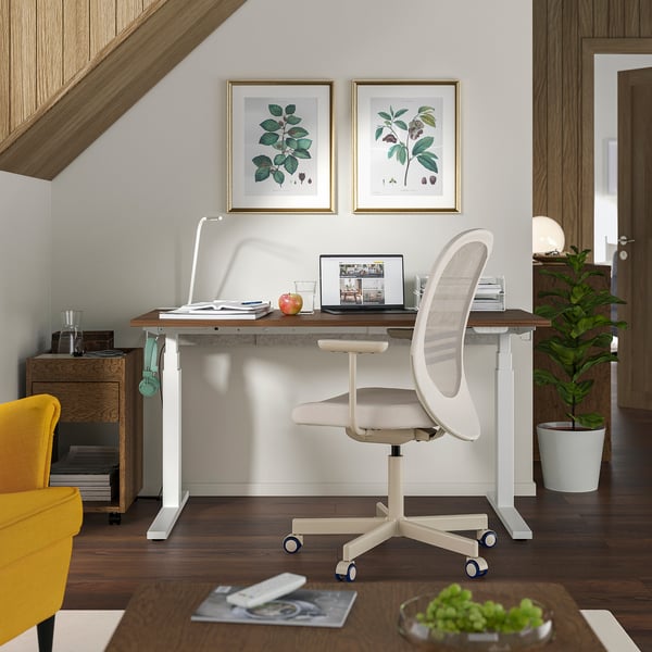 Home office setup with MITTZON standing desk and grönfjäll chair, white. Include laptop, books, apple, yellow chair, plant.
