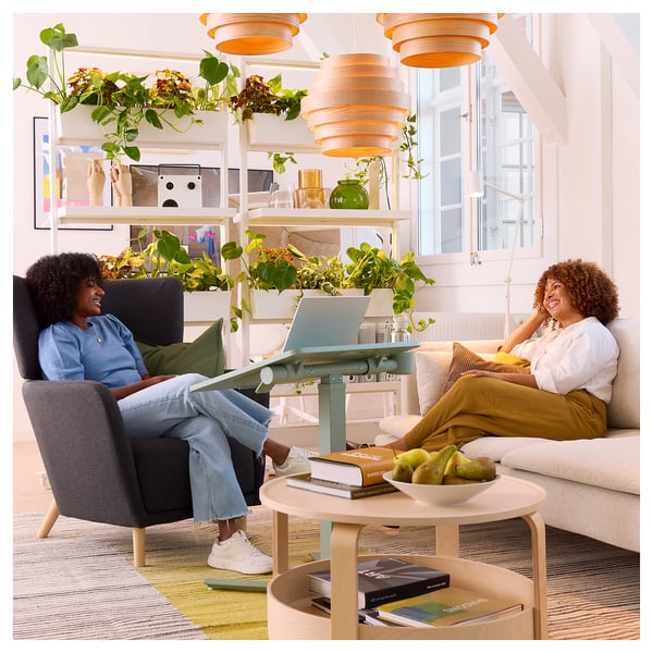 Two people laugh together in a stylish living room with a blue MITTZON laptop table.
