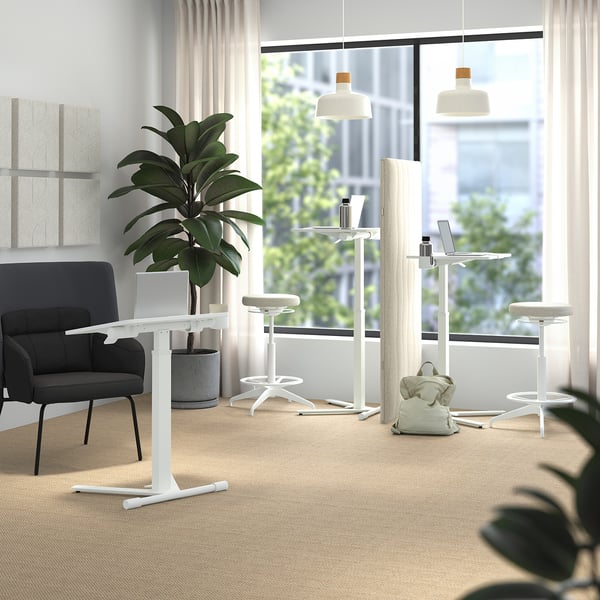 Modern office with MITTZON adjustable tables, white stools, green plant, and city view.