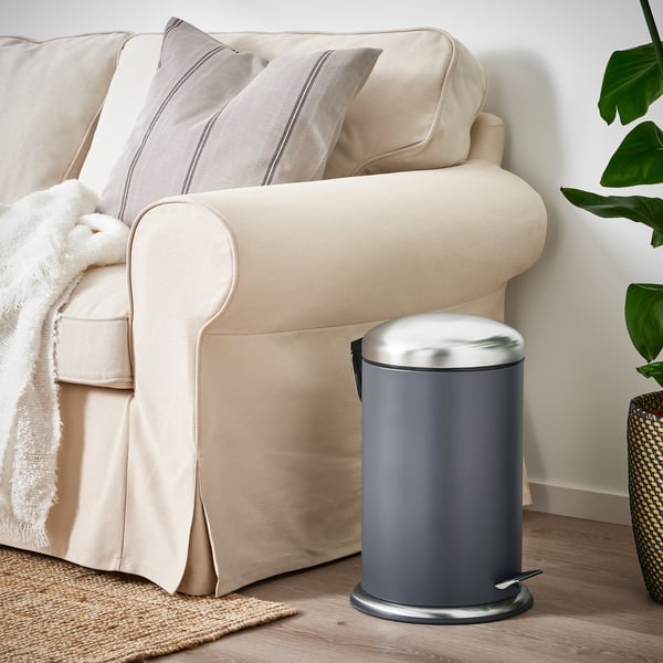 Grey MJÖSA bin beside couch, sleek & compact.