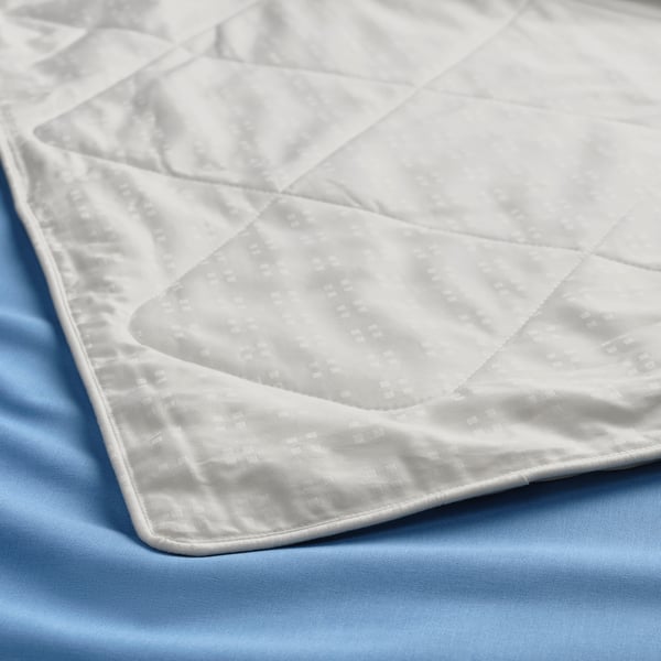 Close-up of a luxurious, smoothly textured white silk duvet on a blue sheet, showcasing its high-quality fabric and craftsmanship.