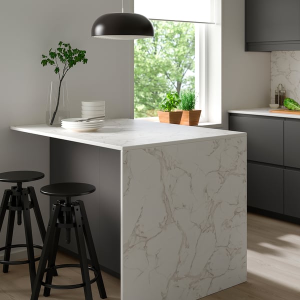 Modern kitchen island with MÖCKLARP porcelain top, marble patterns, pendant light.