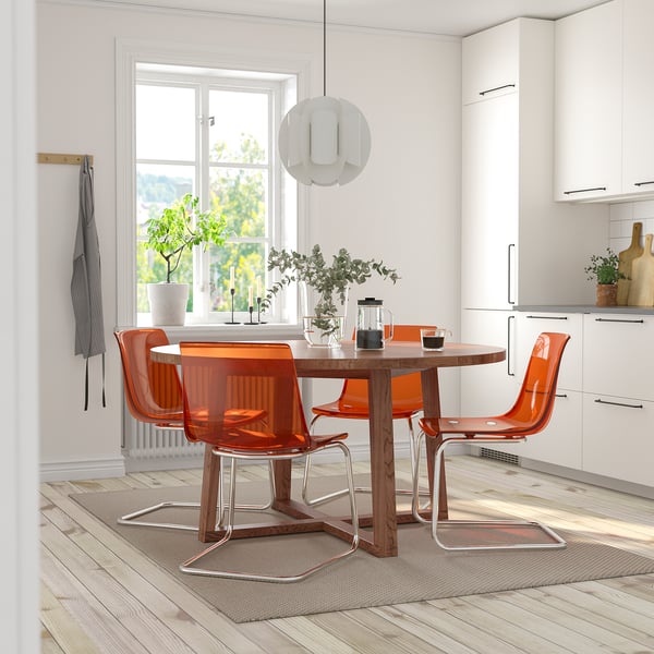 Bright orange MÖRBYLÅNGA chairs circle a wooden table under a white pendant light in a cosy dining nook with a large window.