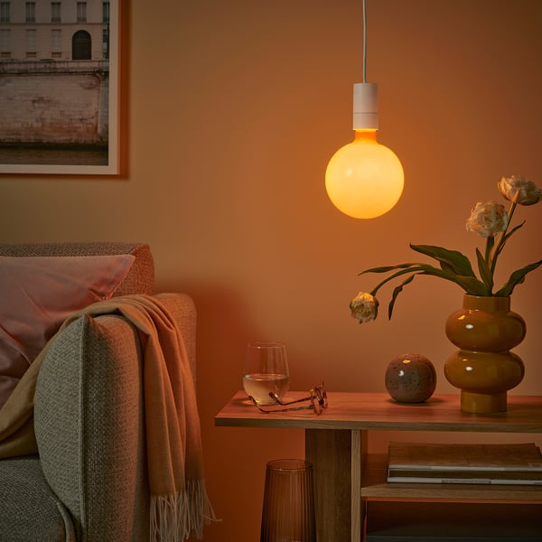 Cosy living room with orange walls, soft yellow light, and decorated table with chair.