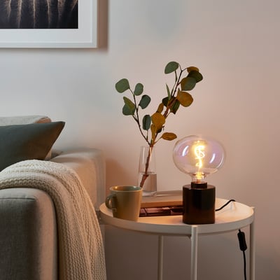 Cosy living room with MOLNART lamp, eucalyptus, and mug on side table beside sofa.