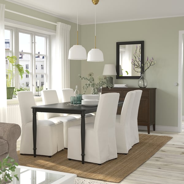 Modern dining room with vibrant lights, black table, white chairs, plush couch, and large windows.