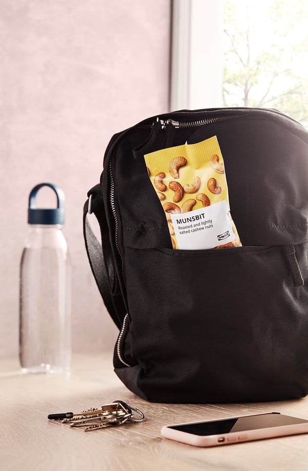 Black backpack on desk with water bottle, keys, and phone.