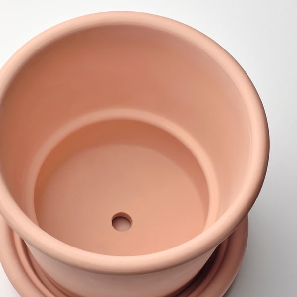 Top view of terracotta planter, smooth surface, small drainage hole visible.