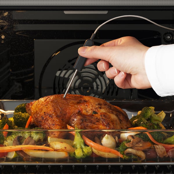 Cooking chicken in oven with meat thermometer.