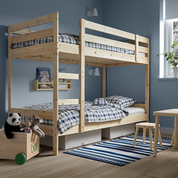 Wooden bunk bed with blue bedding, panda toy, books. Fits cozy blue room with rug and stools.