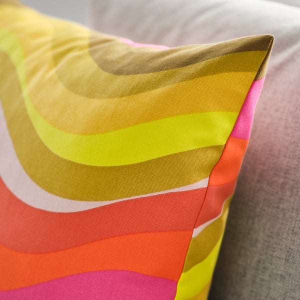 Brightly coloured cushion cover with smooth fabric, wavy pattern in shades of yellow, orange, and pink.