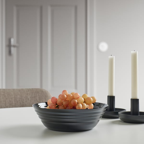 Black NÄTBARB bowl with grapes on white table, candle holders.