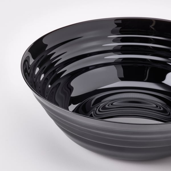 Round black glossy bowl, smooth surface, reflects light, sits on white surface.