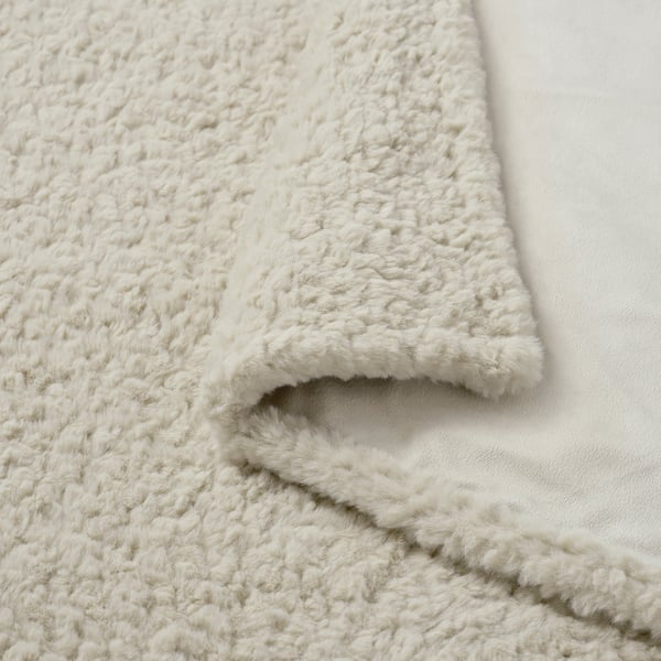 Fluffy white blanket, soft and inviting texture, draped on a white surface.